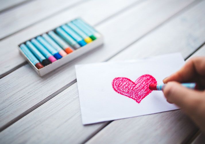 person drawing heart on paper