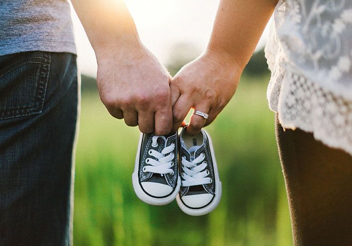 man and woman holding baby shoes in hands